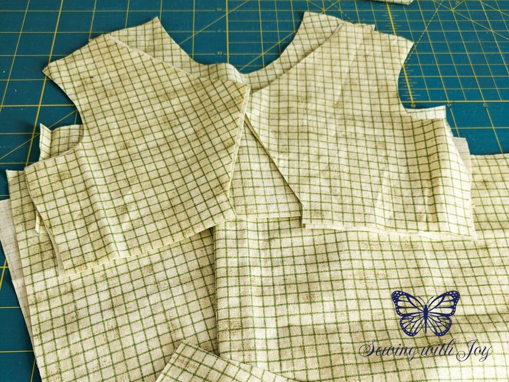 Pattern pieces cut from green fabric with stripes running with horizontally and vertically.