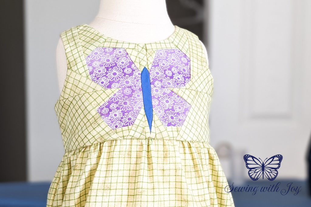 Green romper with a purple and blue Foundation Paper Pieced butterfly on the bodice.